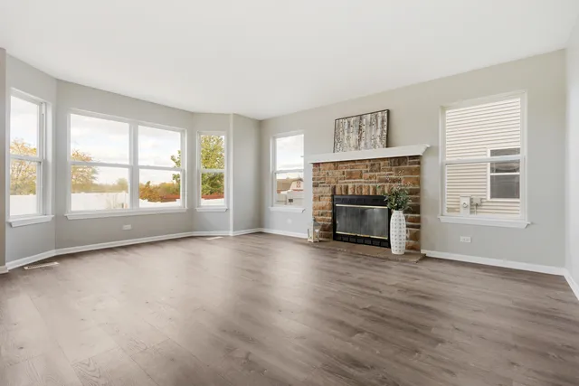 an empty room with windows and fireplace