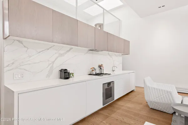 a kitchen with stainless steel appliances a sink a stove and white cabinets with wooden floor