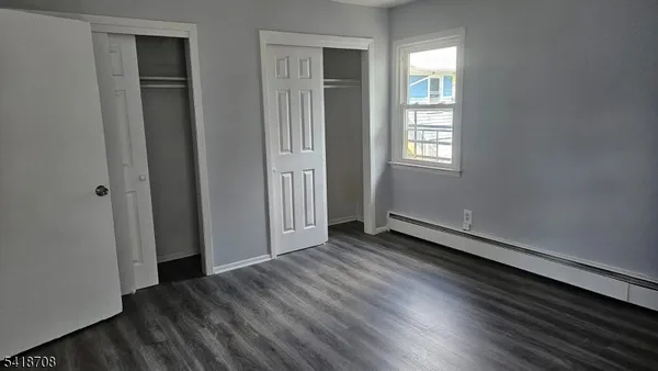 an empty room with wooden floor closet and windows