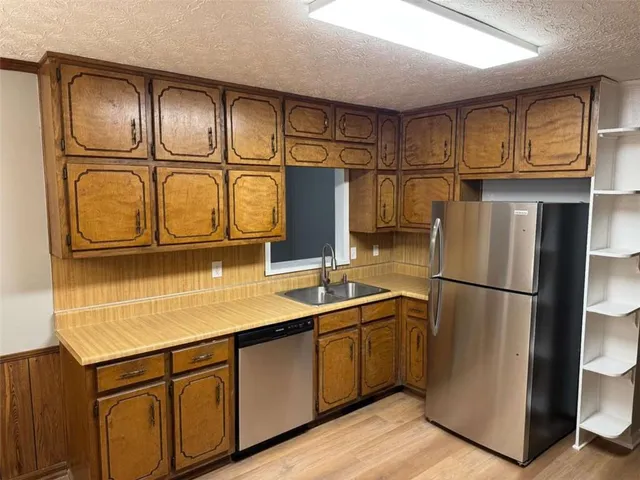 a kitchen with stainless steel appliances granite countertop a refrigerator a sink and cabinets