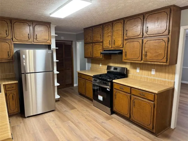 a kitchen with wooden cabinets stainless steel appliances and a refrigerator