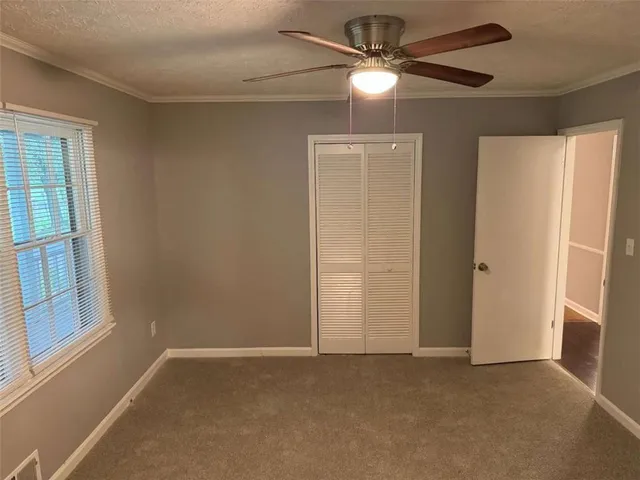 an empty room with windows and fan