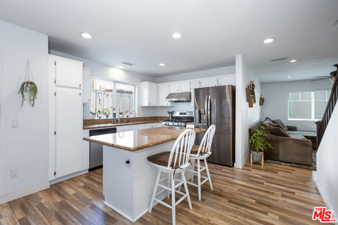 12248 Willowbend Lane Sylmar, CA 91342 - Photo 11 of 52 a kitchen with stainless steel appliances a refrigerator a stove a sink dishwasher with a dining table and chairs