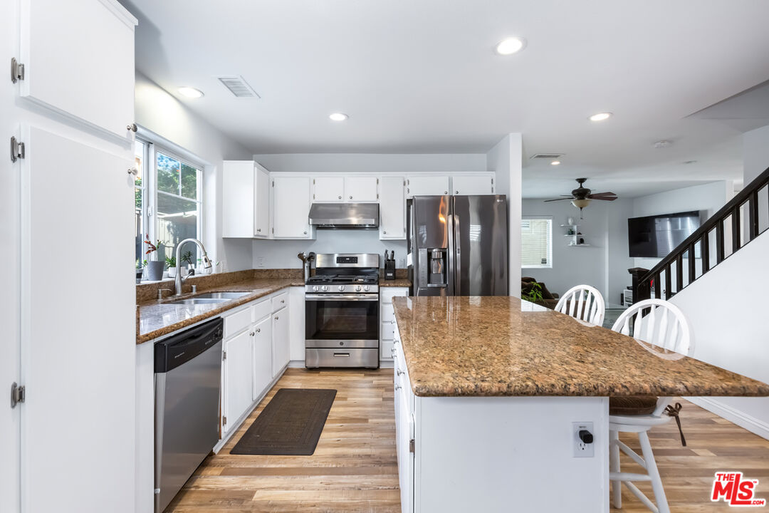 12248 Willowbend Lane Sylmar, CA 91342 - Photo 12 of 52 a kitchen with stainless steel appliances granite countertop a kitchen island hardwood floor sink stove and refrigerator