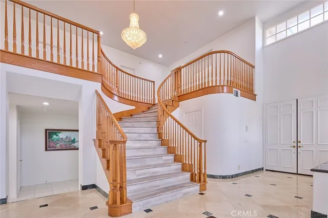 a view of staircase with lots of frames on wall and a chandelier