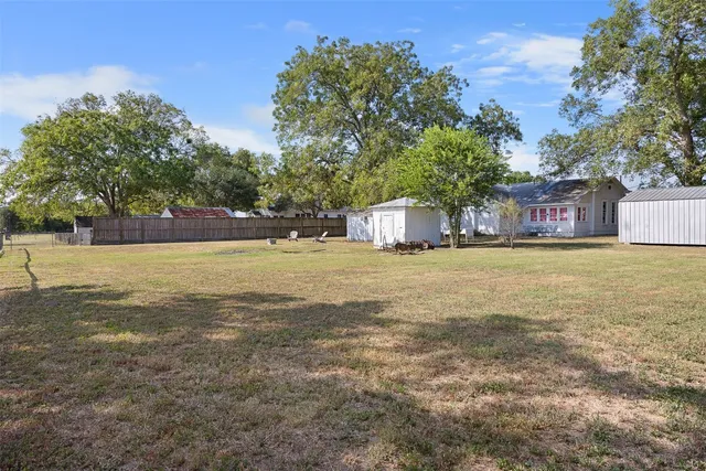a view of a house with yard and trees in the background