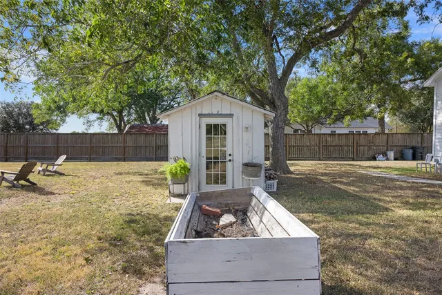 a view of a backyard with a large tree and wooden fence