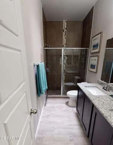 a bathroom with a granite countertop sink a toilet and shower