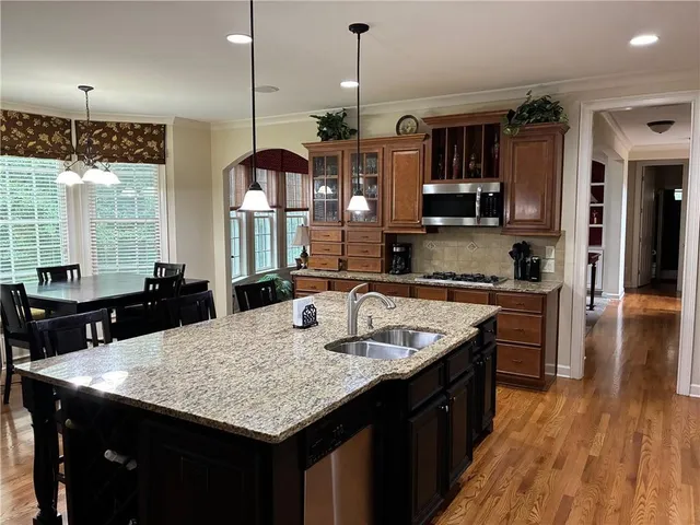 a kitchen with granite countertop kitchen island stainless steel appliances a sink stove and wooden floor