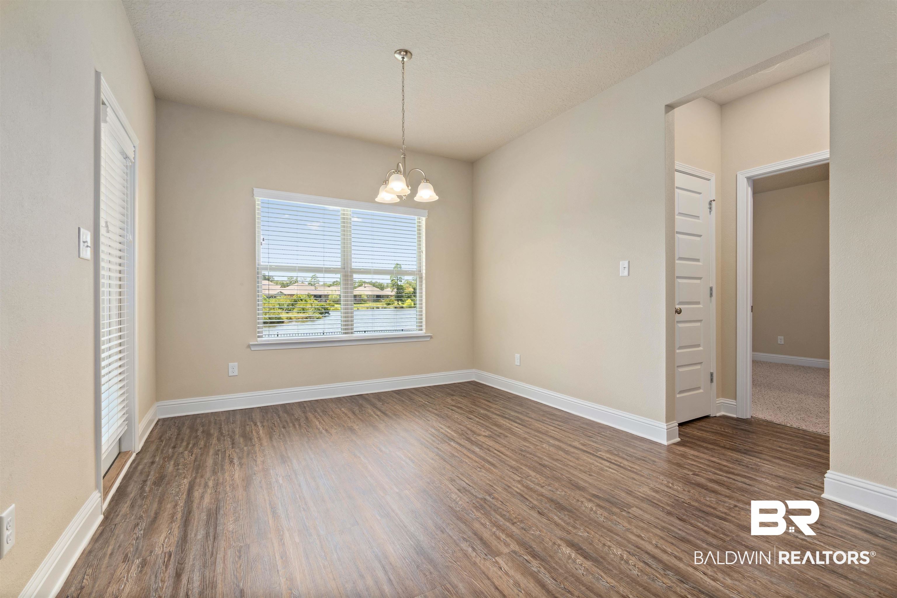 1864 Gwin Court Mobile, AL 36695 - Photo 14 of 37 Empty room with an inviting chandelier and dark hardwood / wood-style flooring
