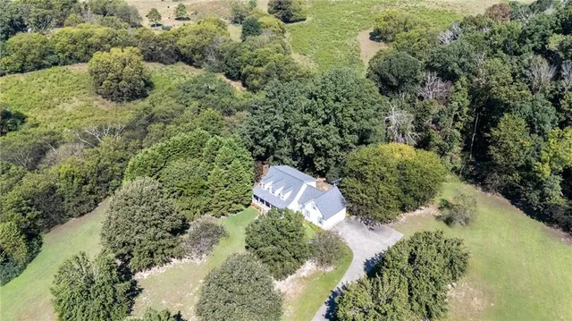 an aerial view of a house with a yard and large trees