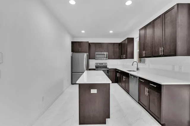 a kitchen with kitchen island granite countertop wooden cabinets a sink and a stove