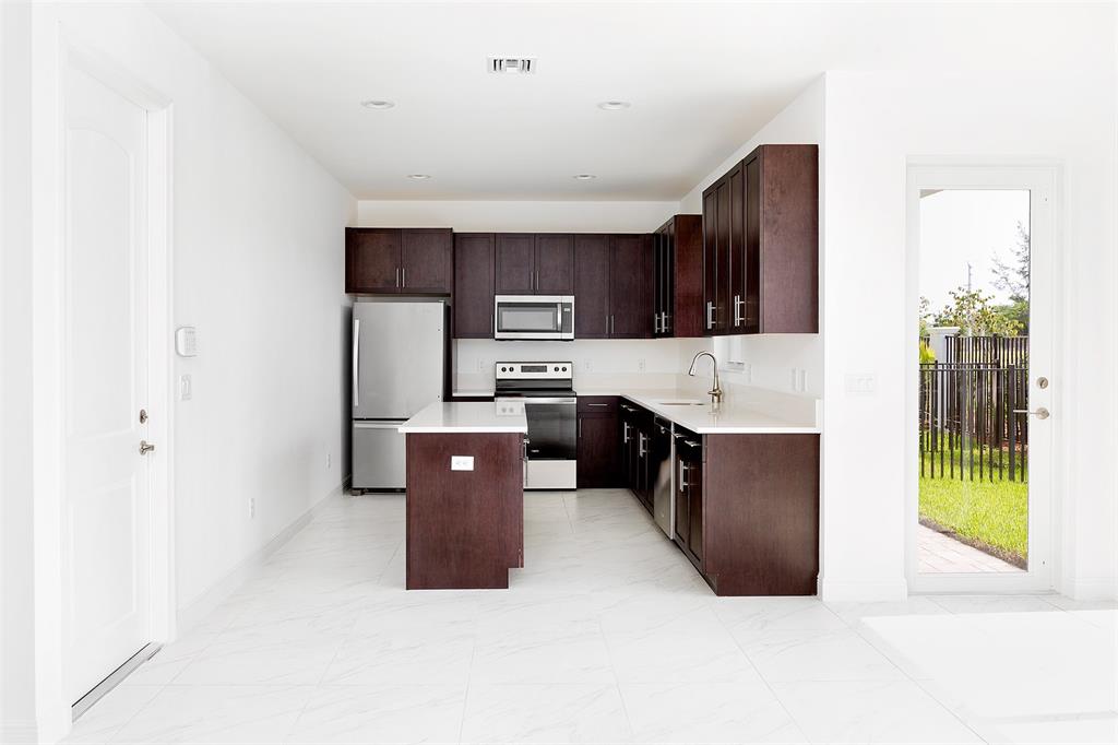 6947 Pines Circle, Unit 21 Pompano Beach, FL 33073 - Photo 12 of 31 a kitchen with stainless steel appliances a refrigerator and a sink