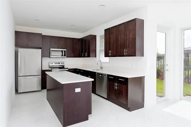 a kitchen with stainless steel appliances granite countertop a refrigerator a stove a sink and a microwave