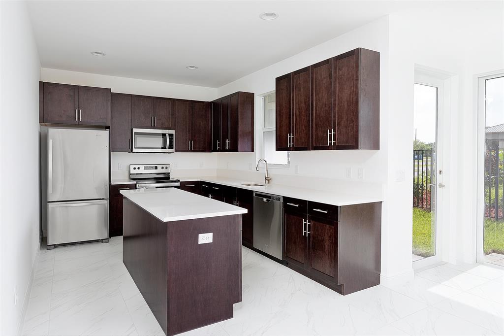 6947 Pines Circle, Unit 21 Pompano Beach, FL 33073 - Photo 13 of 31 a kitchen with stainless steel appliances granite countertop a refrigerator a stove a sink and a microwave
