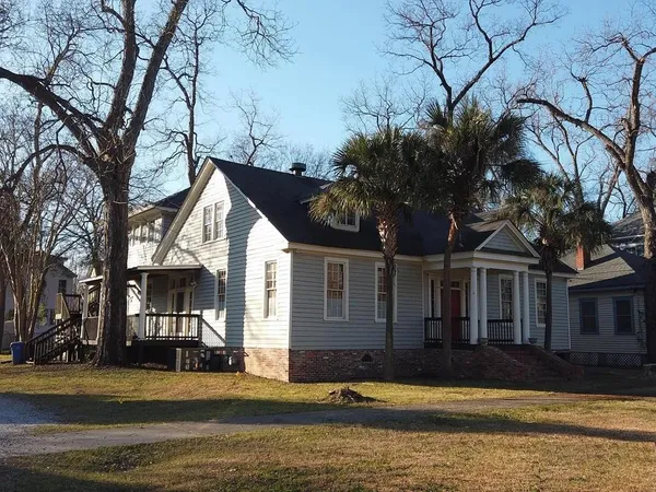 a front view of a house with a garden and trees