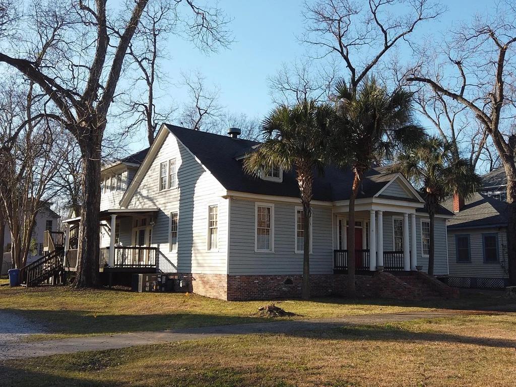 a front view of a house with a garden and trees