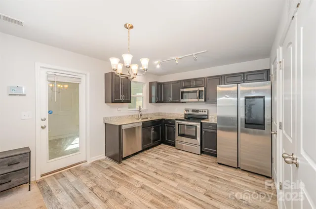 a kitchen with stainless steel appliances granite countertop a refrigerator and a stove top oven