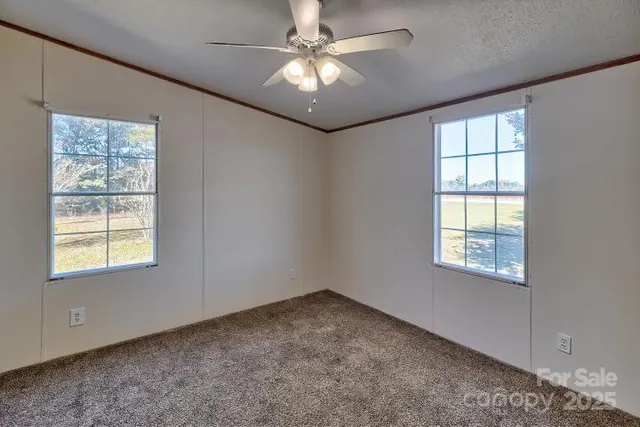 an empty room with windows and fan