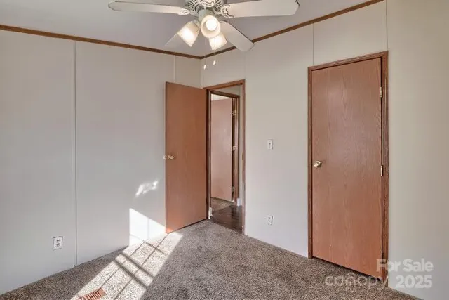 an empty room with closet and a chandelier fan