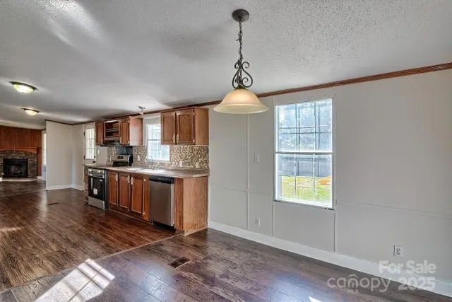 a kitchen with stainless steel appliances granite countertop a stove a sink dishwasher a refrigerator and a dining table with wooden floor