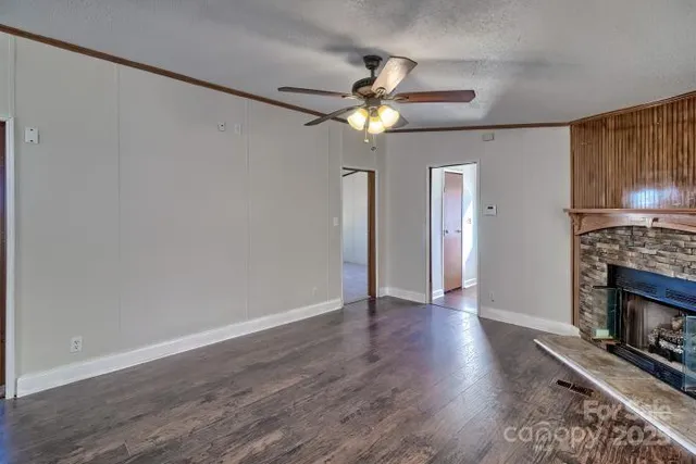 a view of an empty room with wooden floor a fireplace and a window