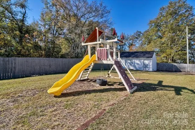 a view of a backyard with a slide and wooden fence