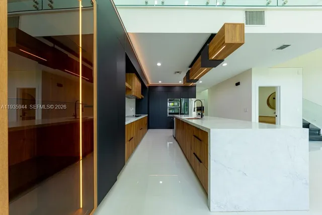 a large kitchen with stainless steel appliances a large counter top and a large window