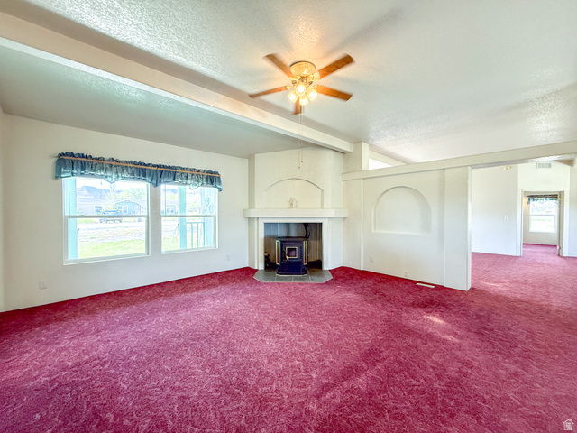 141 South 100 East Emery, UT 84522 - Photo 4 of 17 Living area featuring a central fireplace with an arched mantel, wood-burning stove, and slate-style hearth
