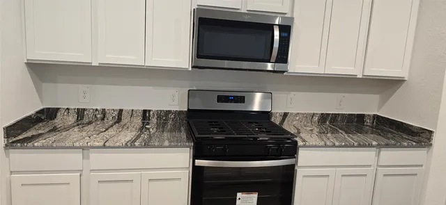 a kitchen with white cabinets and black appliances