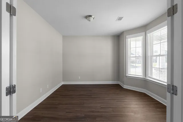 a view of an empty room with wooden floor and a window