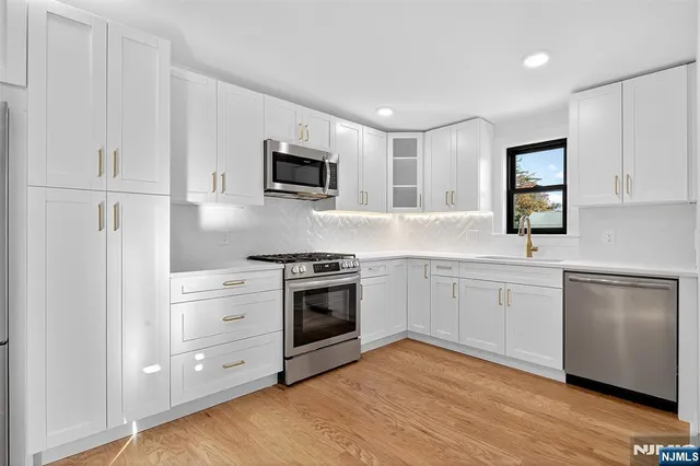 a kitchen with cabinets stainless steel appliances and wooden floor