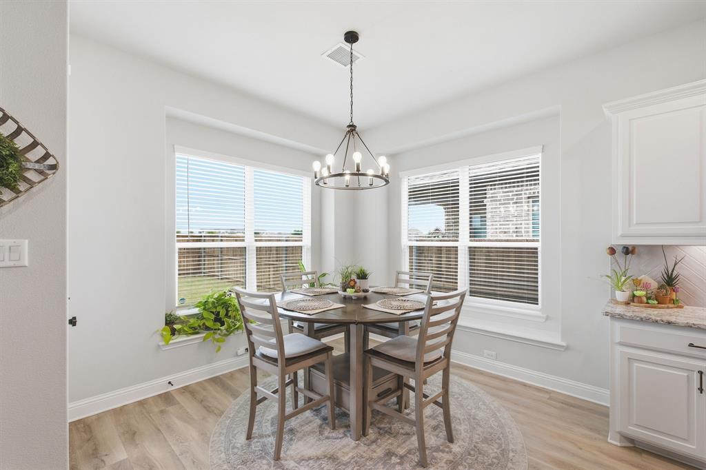 313 Tate Lane Anna, TX 75409 - Photo 11 of 30 Dining area featuring wood-finish flooring, a contemporary chandelier, and multiple windows providing ample natural light