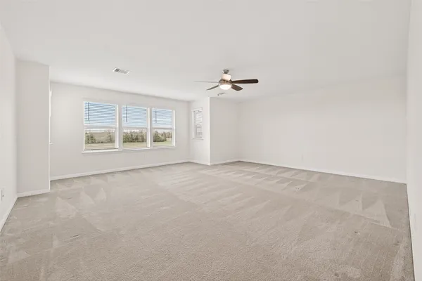 an empty room with a ceiling fan and carpet