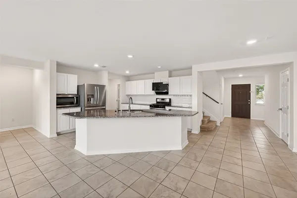 a kitchen with stainless steel appliances granite countertop a refrigerator a stove a sink a microwave and island