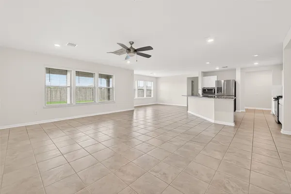 a view of an empty room with a window and a kitchen