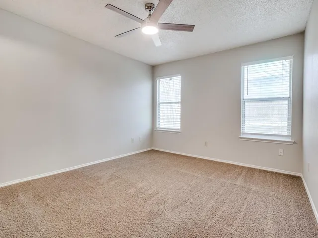 an empty room with a window and ceiling fan