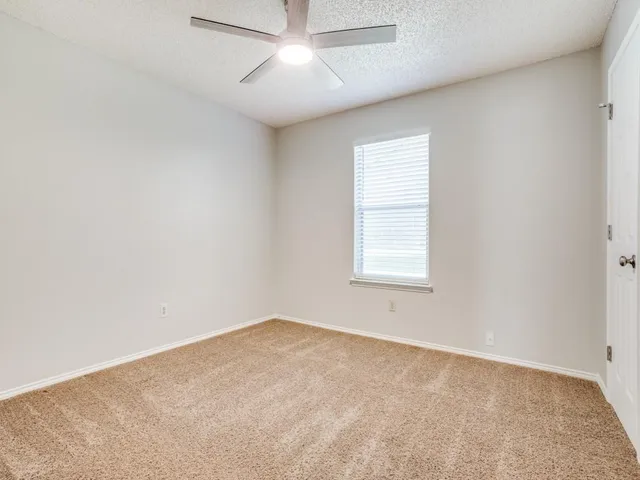 an empty room with a window and ceiling fan