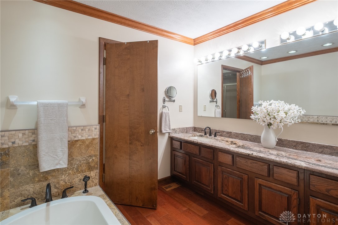 273 North Alpha Bellbrook Road Dayton, OH 45434 - Photo 24 of 43 This bathroom features elegant granite counters, a double vanity, and rich hardwood flooring for a refined feel.