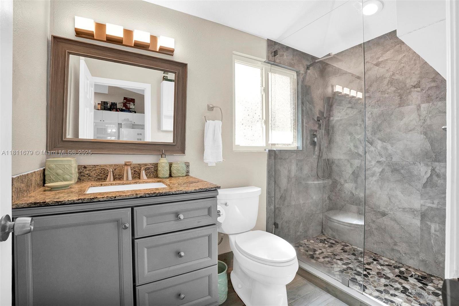 812 Chukker Road, Unit 3 Delray Beach, FL 33483 - Photo 8 of 20 a bathroom with a granite countertop sink toilet a mirror and shower