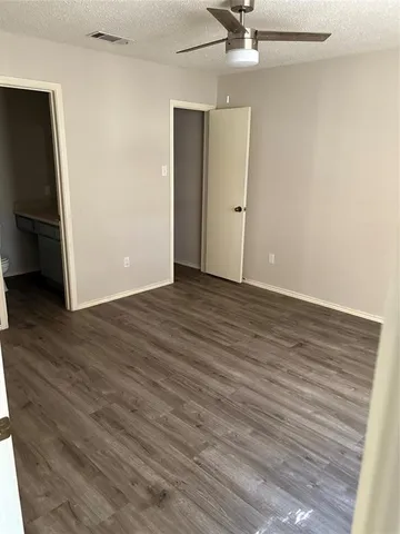 a view of a room with wooden floor and a ceiling fan