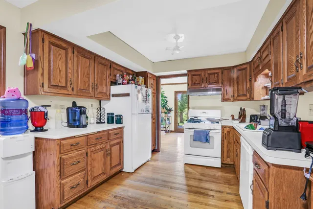 a kitchen with a refrigerator a stove top oven a sink dishwasher and wooden cabinets with wooden floor