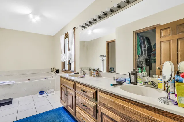 a spacious bathroom with a double vanity sink a mirror and a bathtub