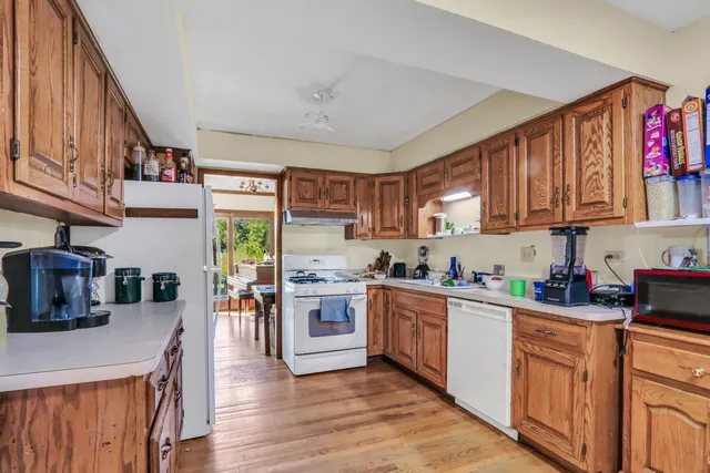 a kitchen with stainless steel appliances granite countertop a refrigerator a stove top oven a sink dishwasher and wooden cabinets with wooden floor