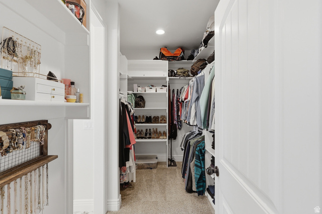 10676 Urban Rdg Cove South Jordan, UT 84095 - Photo 12 of 48 Spacious walk-in closet featuring built-in white shelving, multiple hanging rods, and carpet flooring