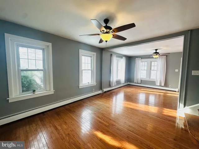 a view of an empty room with window and wooden floor