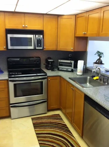 a kitchen with stainless steel appliances granite countertop a sink a stove and a refrigerator