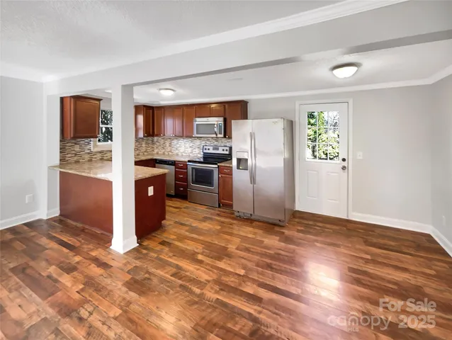 a view of kitchen with stainless steel appliances granite countertop a refrigerator and a stove top oven