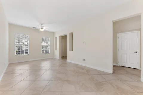 a view of an empty room with windows and chandelier fan