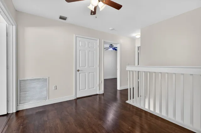 an empty room with wooden floor fan and windows